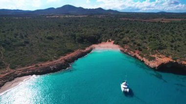 4K Hava Aracı 'nın en inanılmaz turkuaz mavi su renginde kayalık bir formasyon ve güneşli bir yaz gününde demirlenmiş tekneler Cala Varques, Mallorca' da gözlerden uzak bir plaj.