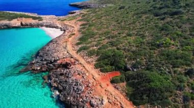 4K Hava Aracı 'nın en inanılmaz turkuaz mavi su renginde kayalık bir formasyon ve güneşli bir yaz gününde demirlenmiş tekneler Cala Varques, Mallorca' da gözlerden uzak bir plaj.