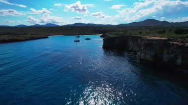 4K Hava Aracı 'nın en inanılmaz turkuaz mavi su renginde kayalık bir formasyon ve güneşli bir yaz gününde demirlenmiş tekneler Cala Varques, Mallorca' da gözlerden uzak bir plaj.