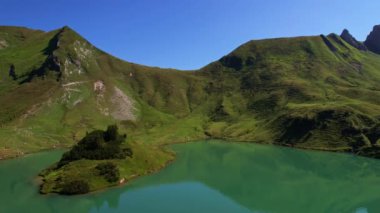 4K Hava Aracı Schrecksee Dağı 'nın en güzel dağ gölünün videosu Bavyera Alpleri' nde güneşli bir günde yemyeşil çimlerle beslenen ineklerle mavi gökyüzü ve etrafındaki kayalık tepelerle çevrili.