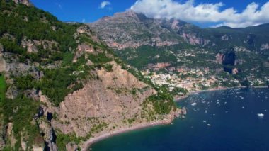 4K Hava Aracı, güneşli bir günde, Positano, İtalya 'nın ünlü Amalfi kıyılarında, çevresindeki dağlarda renkli evler ve deniz manzaralı sihirli bir kasabanın videosu.