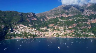 4K Hava Aracı, güneşli bir günde, Positano, İtalya 'nın ünlü Amalfi kıyılarında, çevresindeki dağlarda renkli evler ve deniz manzaralı sihirli bir kasabanın videosu.