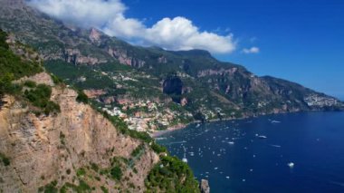 4K Hava Aracı, güneşli bir günde, Positano, İtalya 'nın ünlü Amalfi kıyılarında, çevresindeki dağlarda renkli evler ve deniz manzaralı sihirli bir kasabanın videosu.
