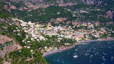 4K Hava Aracı, güneşli bir günde, Positano, İtalya 'nın ünlü Amalfi kıyılarında, çevresindeki dağlarda renkli evler ve deniz manzaralı sihirli bir kasabanın videosu.