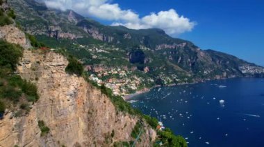 4K Hava Aracı, güneşli bir günde, Positano, İtalya 'nın ünlü Amalfi kıyılarında, çevresindeki dağlarda renkli evler ve deniz manzaralı sihirli bir kasabanın videosu.