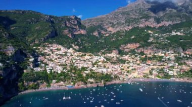 4K Hava Aracı, güneşli bir günde, Positano, İtalya 'nın ünlü Amalfi kıyılarında, çevresindeki dağlarda renkli evler ve deniz manzaralı sihirli bir kasabanın videosu.
