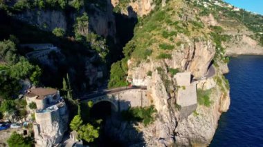 Güneşli bir günde, dar kayalıklarda eşsiz bir köprünün 4K hava manzarası. İtalya 'nın pitoresk Amalfi kıyısındaki ünlü turistik eğlence merkezi Fiordo di Furore