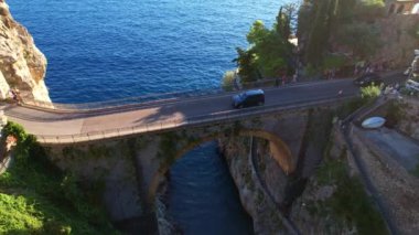 Güneşli bir günde, dar kayalıklarda eşsiz bir köprünün 4K hava manzarası. İtalya 'nın pitoresk Amalfi kıyısındaki ünlü turistik eğlence merkezi Fiordo di Furore