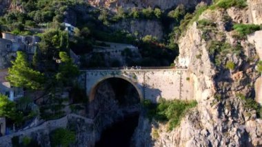 Güneşli bir günde, dar kayalıklarda eşsiz bir köprünün 4K hava manzarası. İtalya 'nın pitoresk Amalfi kıyısındaki ünlü turistik eğlence merkezi Fiordo di Furore