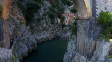 Güneşli bir günde, dar kayalıklarda eşsiz bir köprünün 4K hava manzarası. İtalya 'nın pitoresk Amalfi kıyısındaki ünlü turistik eğlence merkezi Fiordo di Furore