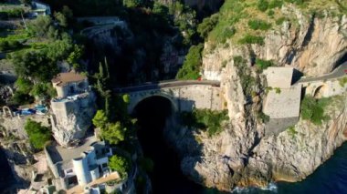 Güneşli bir günde, dar kayalıklarda eşsiz bir köprünün 4K hava manzarası. İtalya 'nın pitoresk Amalfi kıyısındaki ünlü turistik eğlence merkezi Fiordo di Furore