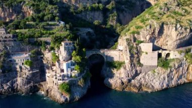 Güneşli bir günde, dar kayalıklarda eşsiz bir köprünün 4K hava manzarası. İtalya 'nın pitoresk Amalfi kıyısındaki ünlü turistik eğlence merkezi Fiordo di Furore