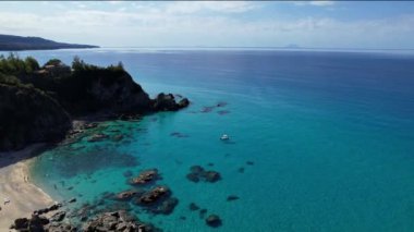 Dünyanın en güzel plajlarından birinin 4K Hava Aracı videosu. Turkuaz berrak mavi su ve güneşli bir yaz gününde büyük kayaları olan beyaz kum. Marinella di Zambrone Paradiso Tropea İtalya