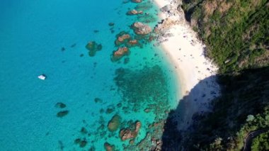 Dünyanın en güzel plajlarından birinin 4K Hava Aracı videosu. Turkuaz berrak mavi su ve güneşli bir yaz gününde büyük kayaları olan beyaz kum. Marinella di Zambrone Paradiso Tropea İtalya