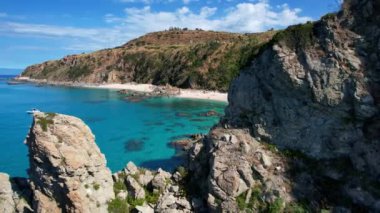 Dünyanın en güzel plajlarından birinin 4K Hava Aracı videosu. Turkuaz berrak mavi su ve güneşli bir yaz gününde büyük kayaları olan beyaz kum. Marinella di Zambrone Paradiso Tropea İtalya