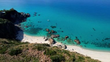 Dünyanın en güzel plajlarından birinin 4K Hava Aracı videosu. Turkuaz berrak mavi su ve güneşli bir yaz gününde büyük kayaları olan beyaz kum. Marinella di Zambrone Paradiso Tropea İtalya