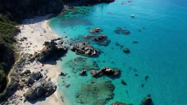 Dünyanın en güzel plajlarından birinin 4K Hava Aracı videosu. Turkuaz berrak mavi su ve güneşli bir yaz gününde büyük kayaları olan beyaz kum. Marinella di Zambrone Paradiso Tropea İtalya