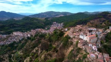 4K hava aracı videosu, gizemli bir görüntüyle tepelerde gerçek dışı bulut şekilleriyle yükseliyor. İtalya 'nın terk edilmiş Tursi kasabası. Boş evleri ve sokakları var.