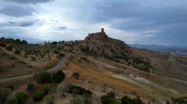 Tepenin tepesinde harabeler ve boş evler olan gizemli hayalet kasabanın 4K hava aracı videosu. Yıkılan yapıları ve yıkılan kilisesi olan lanetli bir köy. Terk edilmiş şehir Craco, Matera, İtalya