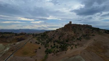 Tepenin tepesinde harabeler ve boş evler olan gizemli hayalet kasabanın 4K hava aracı videosu. Yıkılan yapıları ve yıkılan kilisesi olan lanetli bir köy. Terk edilmiş şehir Craco, Matera, İtalya
