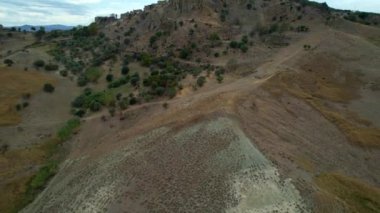 Tepenin tepesinde harabeler ve boş evler olan gizemli hayalet kasabanın 4K hava aracı videosu. Yıkılan yapıları ve yıkılan kilisesi olan lanetli bir köy. Terk edilmiş şehir Craco, Matera, İtalya