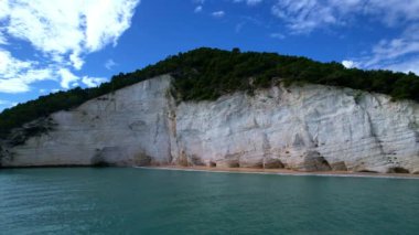 Güneşli bir günde, beyaz yüksek uçurumlar ve turkuaz mavi sularla çevrili en büyüleyici kumlu kumsalın 4K hava aracı videosu. İtalya, Apulia 'daki büyüleyici Vignanotica plajı