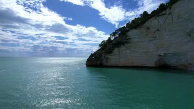 Güneşli bir günde, beyaz yüksek uçurumlar ve turkuaz mavi sularla çevrili en büyüleyici kumlu kumsalın 4K hava aracı videosu. İtalya, Apulia 'daki büyüleyici Vignanotica plajı