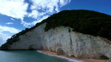 Güneşli bir günde, beyaz yüksek uçurumlar ve turkuaz mavi sularla çevrili en büyüleyici kumlu kumsalın 4K hava aracı videosu. İtalya, Apulia 'daki büyüleyici Vignanotica plajı