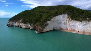 Güneşli bir günde, beyaz yüksek uçurumlar ve turkuaz mavi sularla çevrili en büyüleyici kumlu kumsalın 4K hava aracı videosu. İtalya, Apulia 'daki büyüleyici Vignanotica plajı
