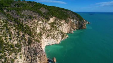 İtalya, Puglia, Apulia 'da güneşli bir yaz gününde en güzel kumlu plajları ve zeytin ağaçlarıyla en güzel beyaz uçurumların 4K hava aracı videosu. Garip daire şekilleri olan ilginç bir sahil.