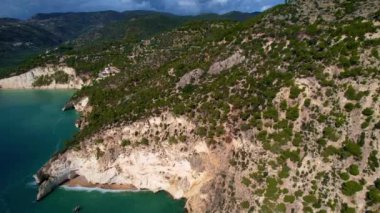 İtalya, Puglia, Apulia 'da güneşli bir yaz gününde en güzel kumlu plajları ve zeytin ağaçlarıyla en güzel beyaz uçurumların 4K hava aracı videosu. Garip daire şekilleri olan ilginç bir sahil.