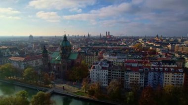 Münih şehir merkezinde güneşli bir günde Isar Nehri, Saint Lukas Kilisesi, Marienplatz ve Maximilianeum ile güzel bir sonbaharın 4K hava aracı videosu, Almanya