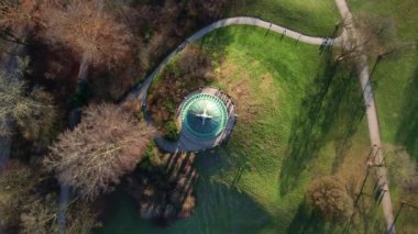 Monopteros ve Çin kulesinin 4K hava aracı videosu, Münih Almanya 'nın tarihi simgeleri güneşli ve sisli bir sonbahar gününde şehir panoramasına bakan İngiliz Bahçesi kamu parkı
