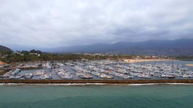 Dünyaca ünlü Santa Barbara 'nın, dramatik bir zemin olarak dağlara bakan hava manzarası. Batı Sahili California USA. Pasifik Okyanusu. Palmiye ağaçları olan kayalıklar ve yüzlerce teknesi olan büyük bir liman.