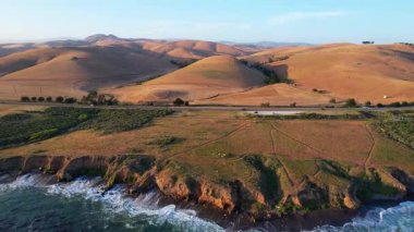 Dünyaca ünlü Karayolu 1 Batı Kıyısı California 'nın havadan görünüşü. Estero Bluffs Eyalet Parkı. Gün batımında dalgalar güzel kayalıklara çarpıyor. Altından bir saat sonra otoyol tam yanında akıyor.