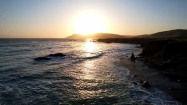 Dünyaca ünlü Karayolu 1 Batı Kıyısı California 'nın havadan görünüşü. Estero Bluffs Eyalet Parkı. Gün batımında dalgalar güzel kayalıklara çarpıyor. Altından bir saat sonra otoyol tam yanında akıyor.