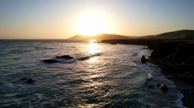 Dünyaca ünlü Karayolu 1 Batı Kıyısı California 'nın havadan görünüşü. Estero Bluffs Eyalet Parkı. Gün batımında dalgalar güzel kayalıklara çarpıyor. Altından bir saat sonra otoyol tam yanında akıyor.