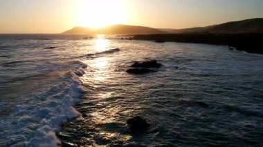 Dünyaca ünlü Karayolu 1 Batı Kıyısı California 'nın havadan görünüşü. Estero Bluffs Eyalet Parkı. Gün batımında dalgalar güzel kayalıklara çarpıyor. Altından bir saat sonra otoyol tam yanında akıyor.