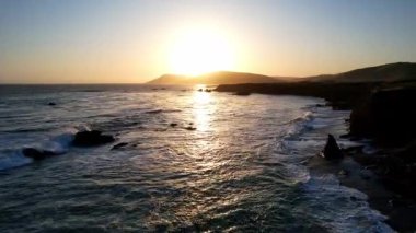 Dünyaca ünlü Karayolu 1 Batı Kıyısı California 'nın havadan görünüşü. Estero Bluffs Eyalet Parkı. Gün batımında dalgalar güzel kayalıklara çarpıyor. Altından bir saat sonra otoyol tam yanında akıyor.