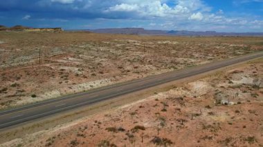 Utah Çölü 'nde nefes kesici kırmızı bir kanyonun 4K Hava Aracı videosu ve eyaletler arası yolda giden arabalar. Zeminin gerçek dışı renginde ve oyulmuş nehir yatağıyla görkemli bir manzara. Birleşik Devletler