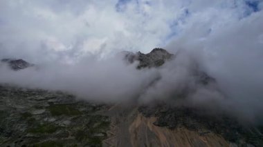 Almanya 'nın en yüksek dağ zirvesine yapılan yürüyüşün 4K Hava Aracı videosu, destansı bulutlar ve inanılmaz doğa ile kasvetli sisli bir günde Zugspitze. Ünlü dağ kulübesi Knorr Hut