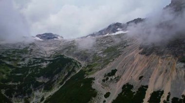 Almanya 'nın en yüksek dağ zirvesine yapılan yürüyüşün 4K Hava Aracı videosu, destansı bulutlar ve inanılmaz doğa ile kasvetli sisli bir günde Zugspitze. Ünlü dağ kulübesi Knorr Hut