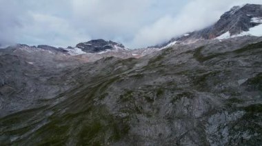 Almanya 'nın en yüksek dağ zirvesine yapılan yürüyüşün 4K Hava Aracı videosu, destansı bulutlar ve inanılmaz doğa ile kasvetli sisli bir günde Zugspitze. Ünlü dağ kulübesi Knorr Hut
