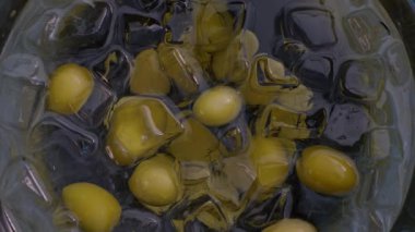 4K yakın çekim, temiz, doğal manikürlü bir kadın eli soğuk su ve buzlu bir kabın içinden taze yeşil bir zeytin çıkarıyor. Yemek ya da kokteyl hazırlıyorum.. 