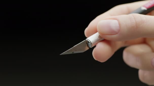 4K特写镜头一个白种人女人的手在手柄上握着一把尖尖的金属银手术刀 她的手有着自然清洁的指甲 在他的手指间打滚 — 图库视频影像