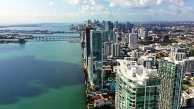 4k 'lık yüksek kalite İHA, güneşli bir günde Atlantik Okyanusu' ndaki mavi-yeşil Biscayne Körfezi 'ne bakan modern yüksek binaların üzerinde yatay olarak uçar. Miami Limanı ufukta görünüyor. Florida