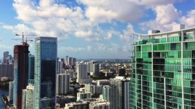 4K hava aracı şehir merkezini gören modern bir cam bina boyunca yatay olarak uçuyor. Miami 'nin prestij bölgesi. Cam ve betondan yapılmış liman kenarı gökdeleni