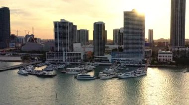 4K lüks yatlar ve günbatımının altın ışıklarıyla körfezdeki yüksek binalar. Ulaşım ve yelkencilik işi için harika bir reklam videosu. Miami 'nin güzel şehir manzarası. ABD