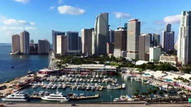 4K drone footage. View from above of the bay with expensive luxury yachts near Ferris wheel in downtown Miami. Beautiful cinematic cityscape of a modern metropolis on a sunny day. Florida. USA