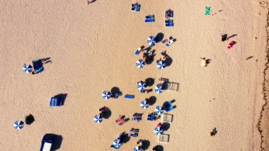 Miami 'de kumlu bir sahilin nefes kesici manzarası mavi ve beyaz şemsiyeler, güneşlenenler ve plaj sandalyeleriyle süslenmiş güneşli bir gökyüzünün altında güzel bir yaz sahnesi yaratıyor. İHA 'dan 4K görüntü